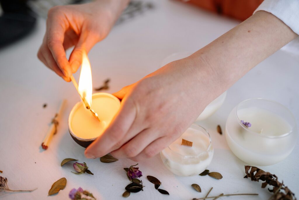 A serene moment captured as hands light a scented candle on a white table.